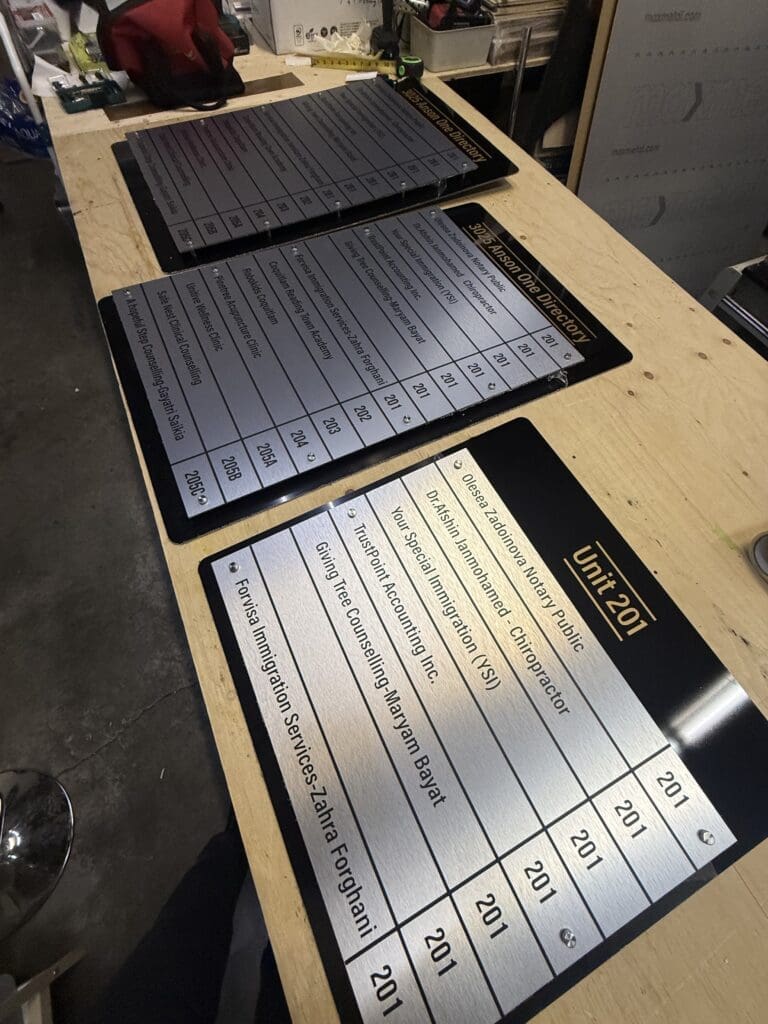 Directory boards preassembled in the workshop with black backings, gold headers and standoff hardware.